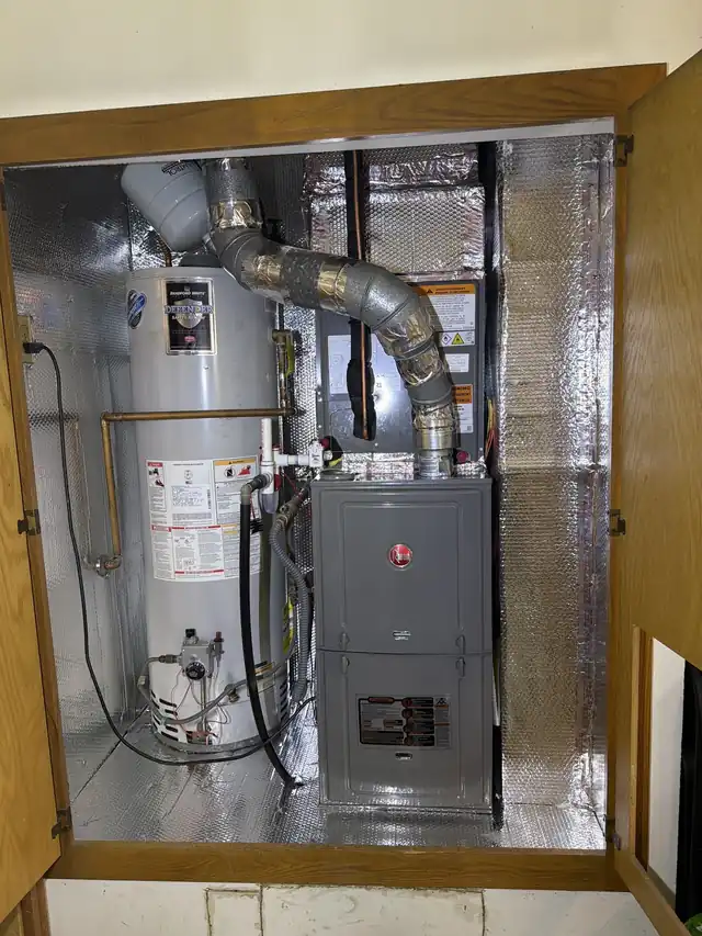 A Rheem gas furnace and a water heater installed in a foil-lined closet with a new flue pipe